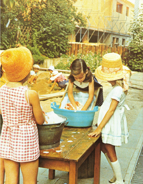 Mädchen waschen Wäsche mit Waschbrett im Zuber.