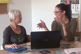 Zwei Frauen unterhalten sich vor einem Laptop.